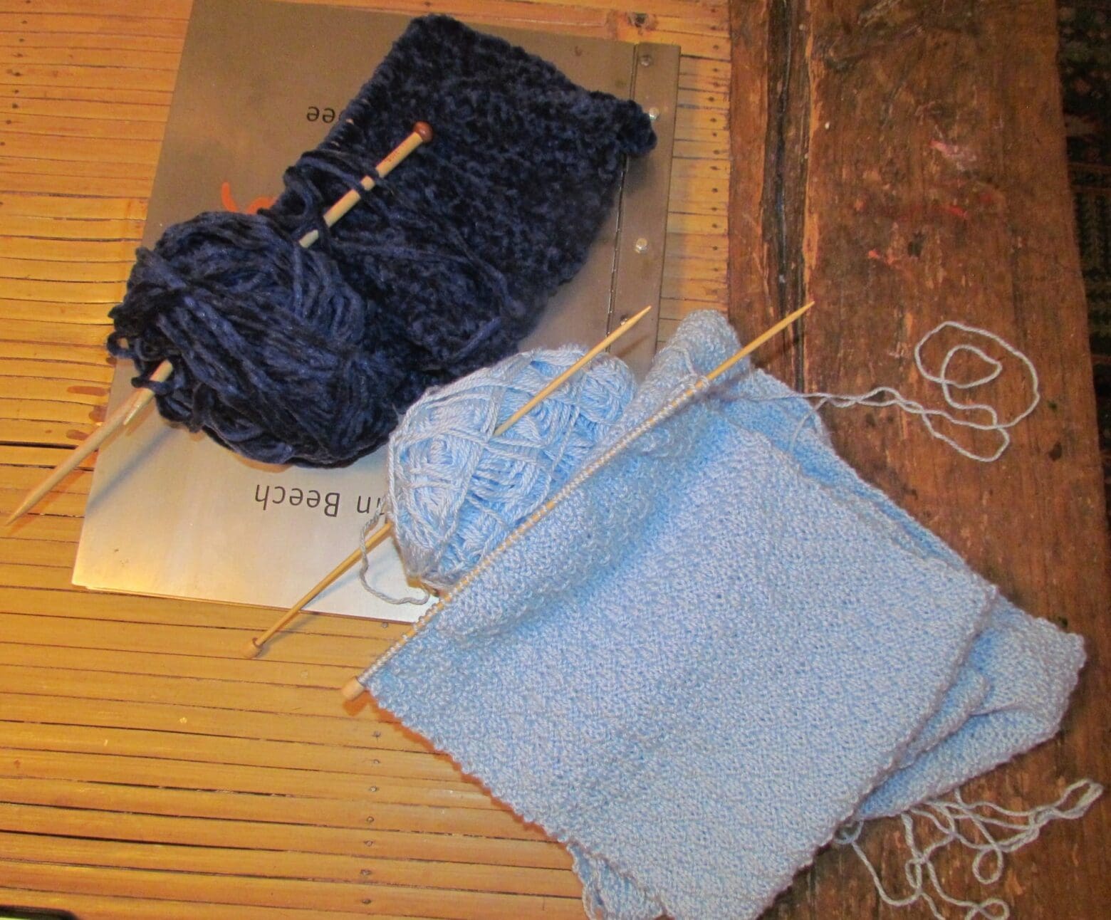 Light blue Scarf in alternating Knit 2, Purl 2 Pattern with Navy Blue Chenille infinity scarf in the background.